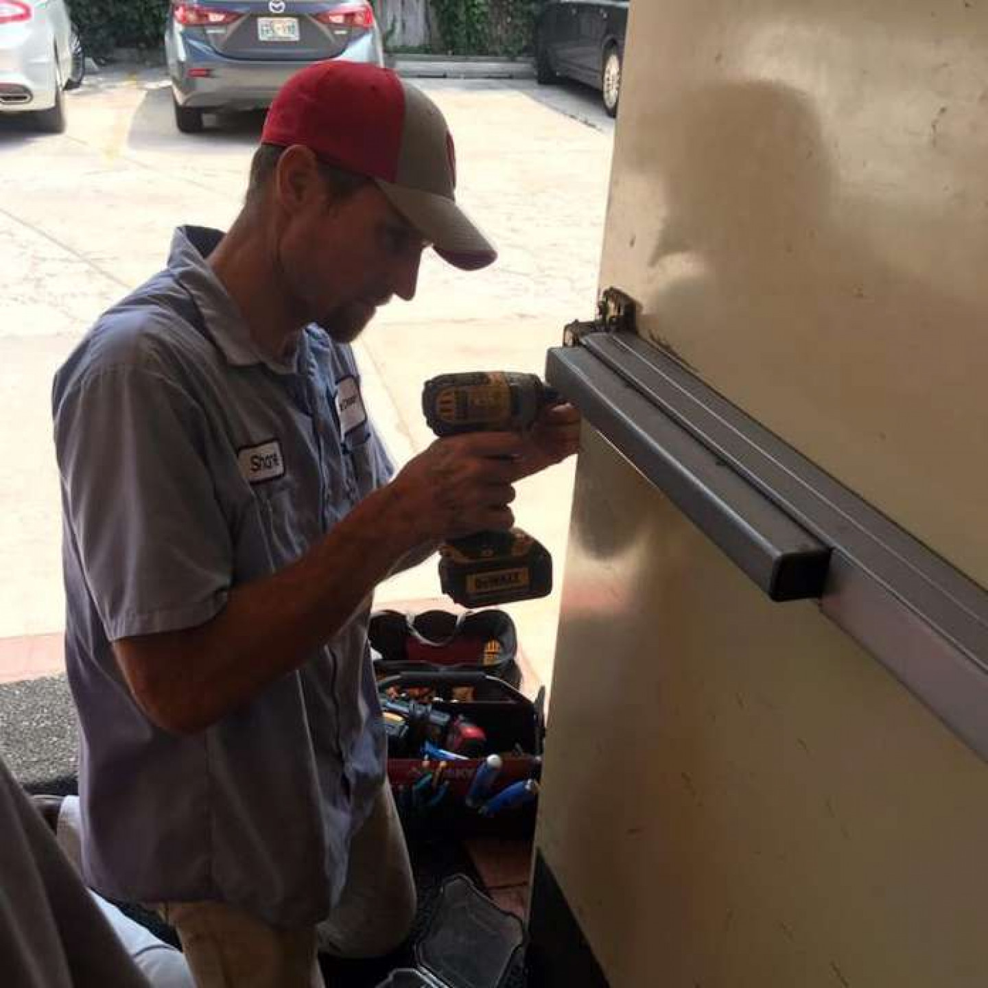 A commercial door technician installing a panic bar device on a hollow metal door