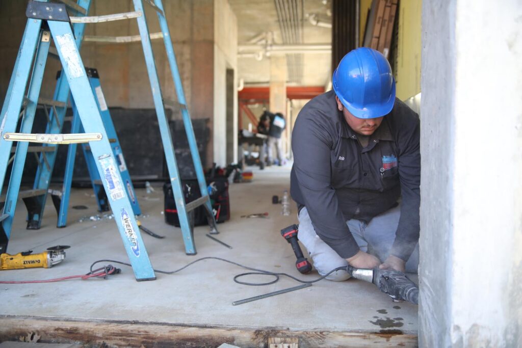 A Commercial Door technician installing a steel door frame in a concrete building